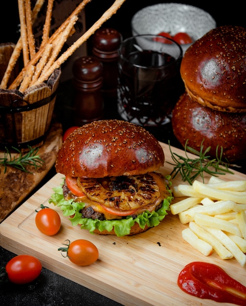 Cheeseburger de carne e batatas fritas em uma placa de madeira