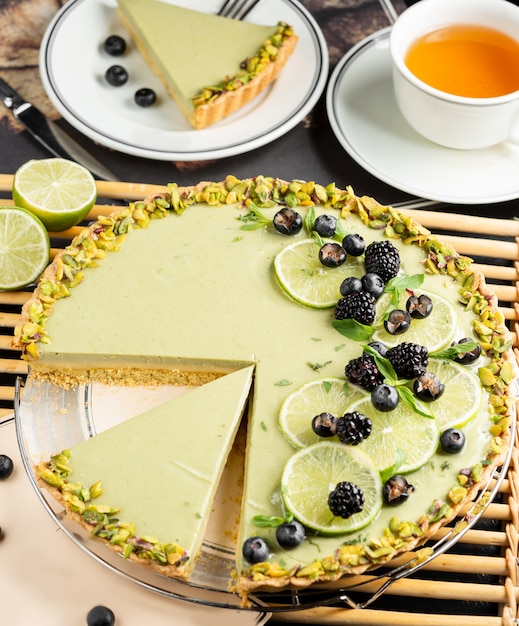 Cheesecake de limão decorado com fatias de limão, amora, groselha preta e pistache