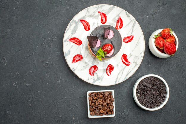 Cheesecake de morango em tigelas de prato oval com sementes de chocolate e café de morango em fundo escuro.