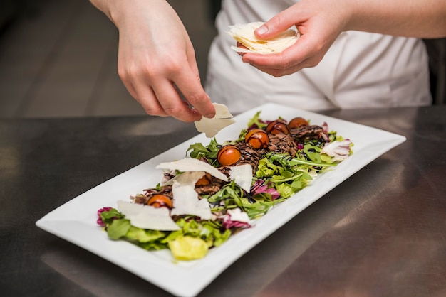 Chef, colocando o queijo fatiado na salada