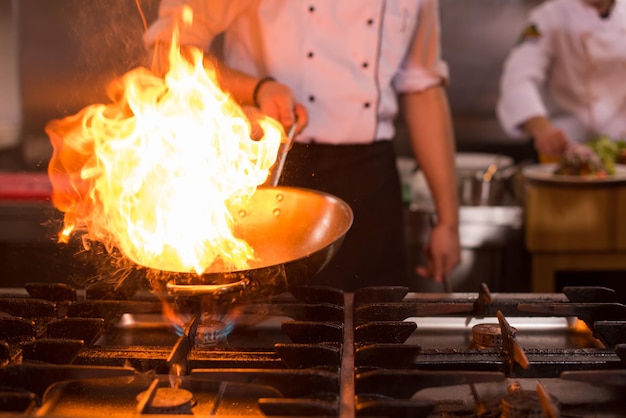 Chef cozinhando e fazendo flambe na comida na cozinha do restaurante