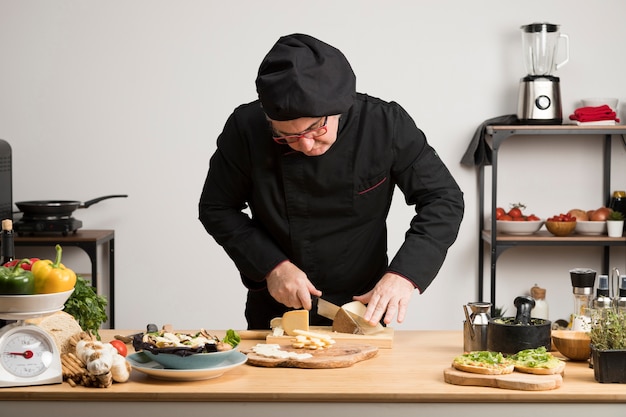 Foto grátis chef de alto ângulo, corte o queijo