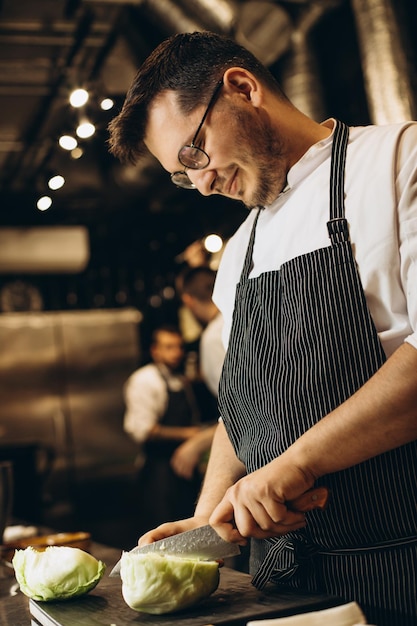 Chef de homem cortando repolho no restaurante da cozinha