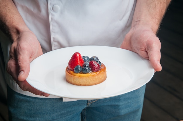 Foto grátis chef de restaurante segurando o prato com doce sobremesa