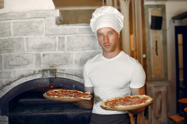 Chef de uniforme branco preparar uma pizzaa