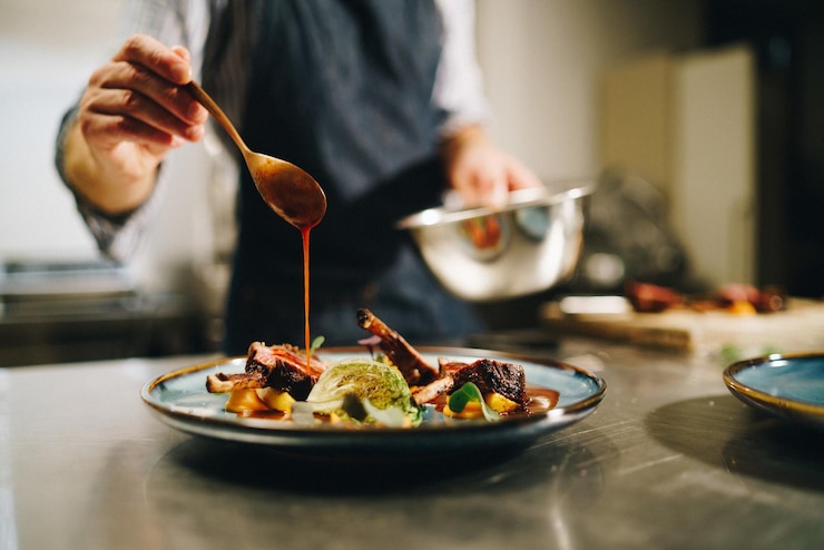 Foto grátis chef derramando molho especial em costelas de porco na cozinha