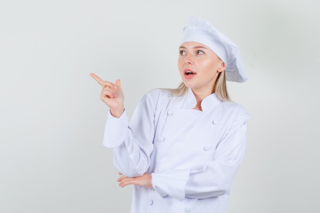 Chef feminina apontando o dedo de uniforme branco e parecendo positiva