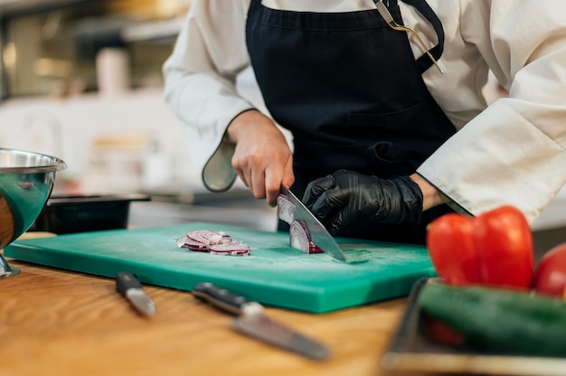 Chef feminina com avental e luva cortando legumes