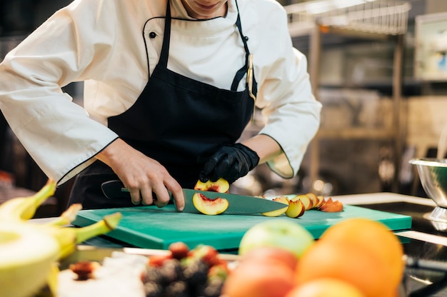 Chef feminina cortando pêssego com luva