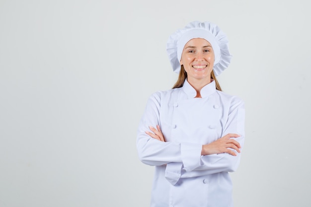 Foto grátis chef feminina de uniforme branco em pé com os braços cruzados e aparência alegre