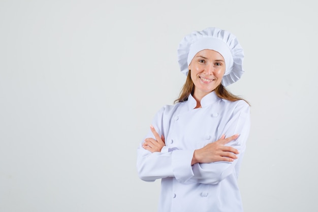 Foto grátis chef feminina em pé com os braços cruzados em um uniforme branco e parecendo feliz