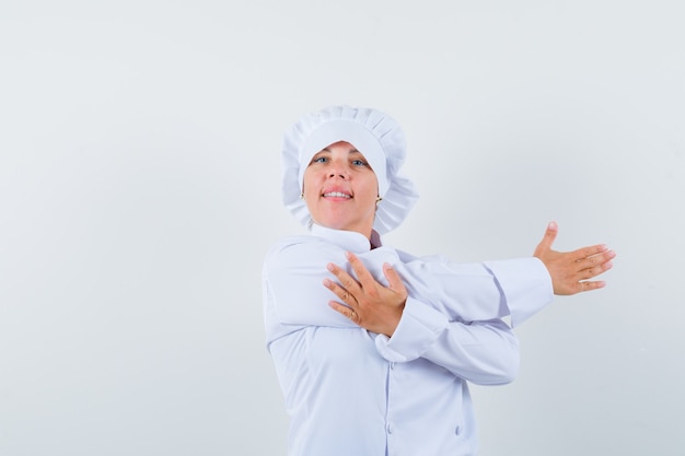 Chef feminina esticando os braços em uniforme branco e parecendo relaxada