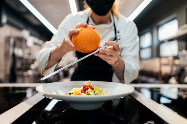 Foto grátis chef feminina ralando casca de laranja no prato