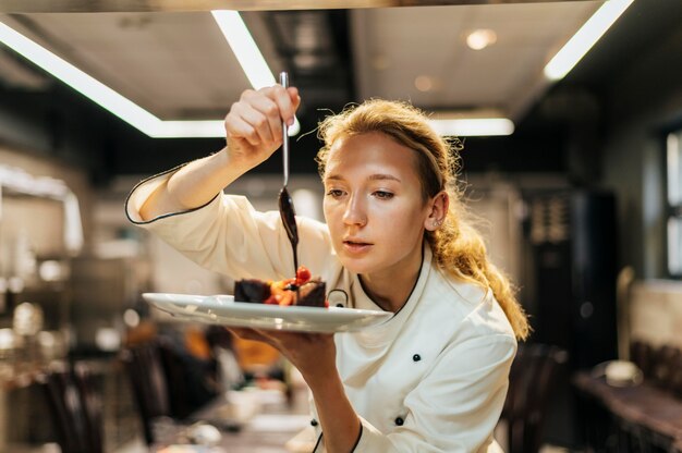 Chef feminina servindo molho com cuidado sobre o prato