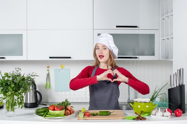 Chef feminino com chapéu de cozinheiro fazendo sinal de coração