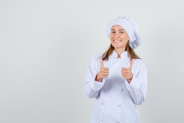 Chef feminino mostrando os polegares em uniforme branco e parecendo feliz. vista frontal.