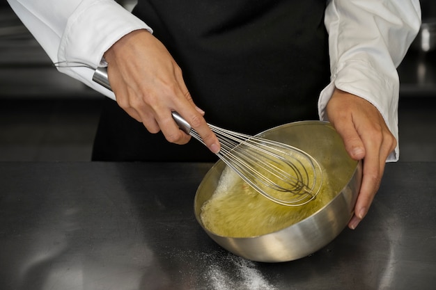 Chef feminino na cozinha batendo ovos com batedor