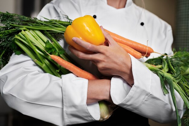 Chef feminino na cozinha segurando legumes