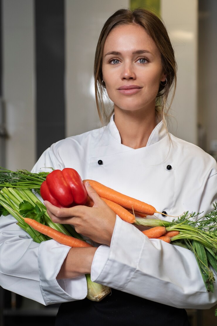 Foto grátis chef feminino na cozinha segurando legumes