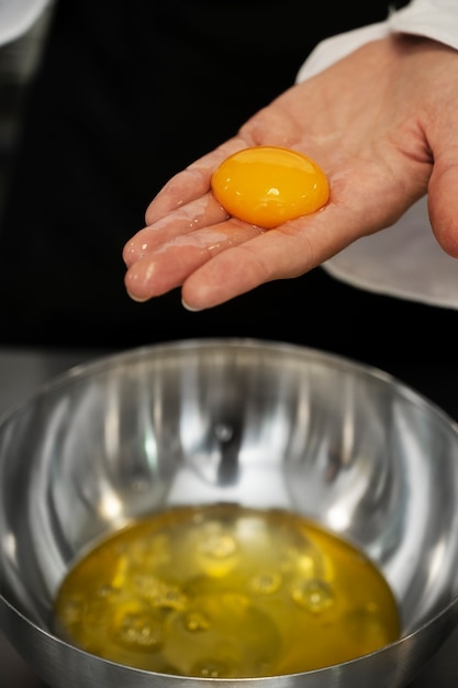 Foto grátis chef feminino na cozinha separando ovos na tigela
