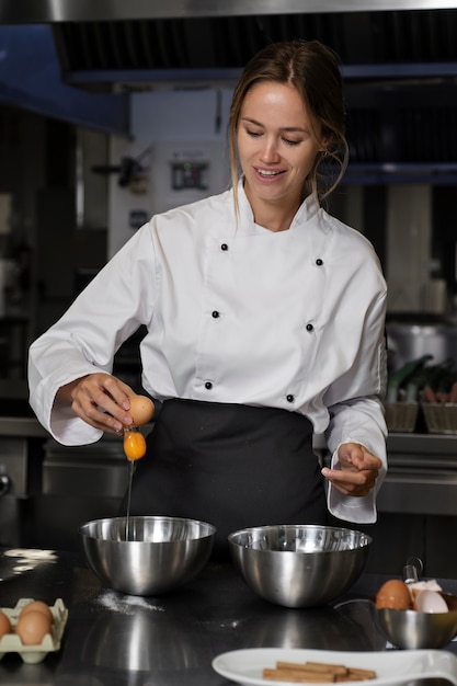 Foto grátis chef feminino na cozinha separando ovos na tigela