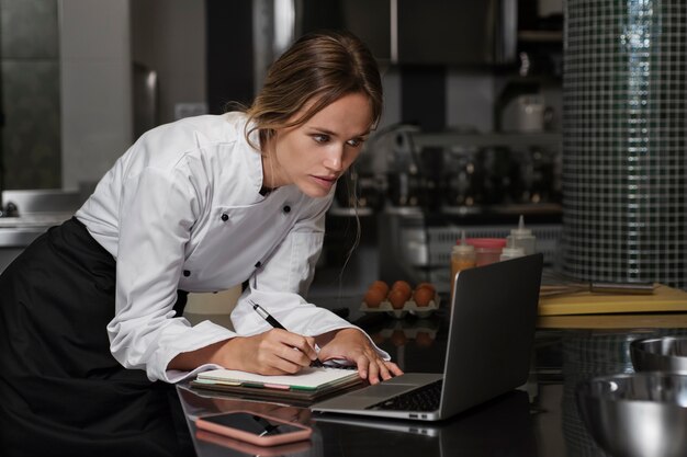 Chef feminino na cozinha usando o dispositivo portátil
