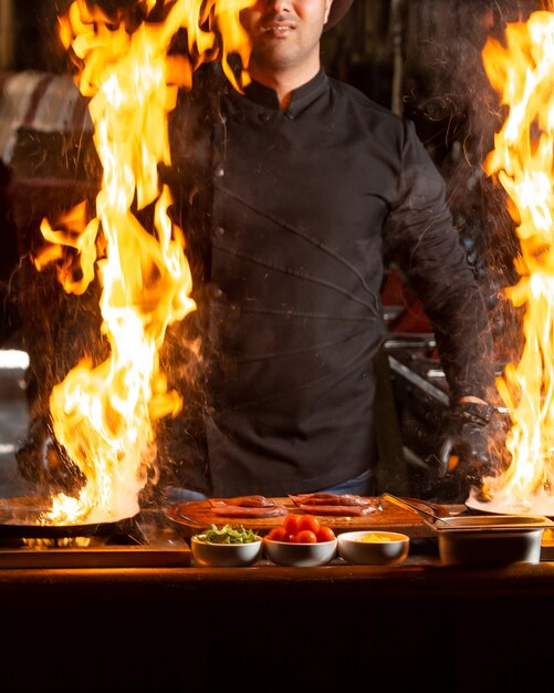 Chef mantém duas frigideiras com fogo ardente