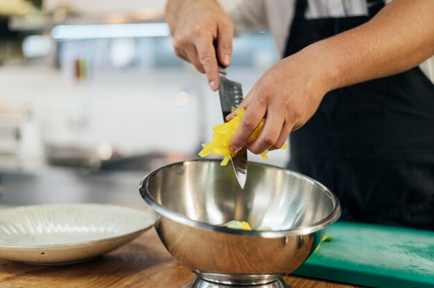 Chef masculino adicionando pimentão picado na tigela