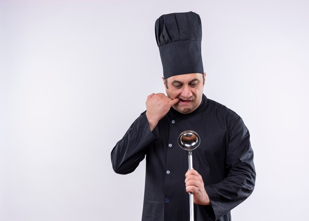 Chef masculino cozinheiro vestindo uniforme preto e chapéu de cozinheiro segurando o padle nervoso e preocupado em pé sobre um fundo branco