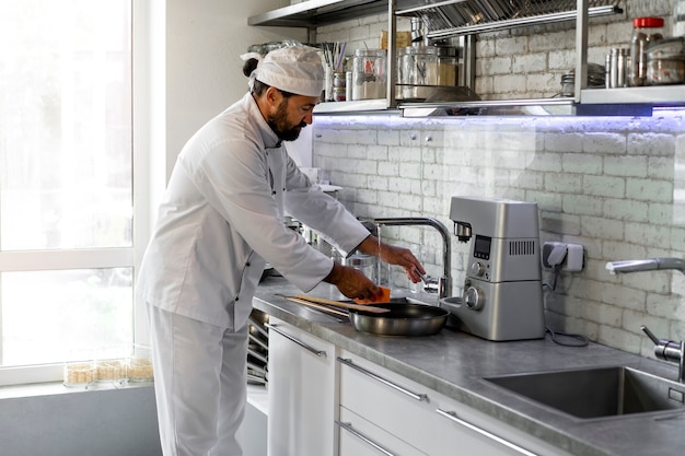 Chef masculino na cozinha lavando frigideira