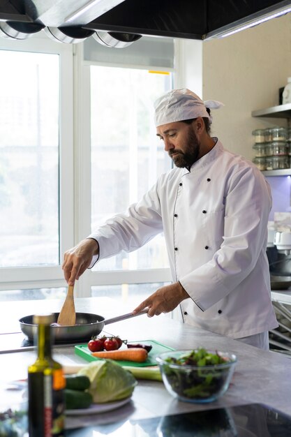 Chef masculino no prato de cozinha em uma frigideira