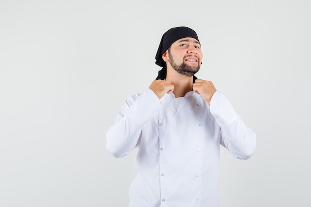 Chef masculino puxando seu colarinho de uniforme branco e elegante vista frontal.