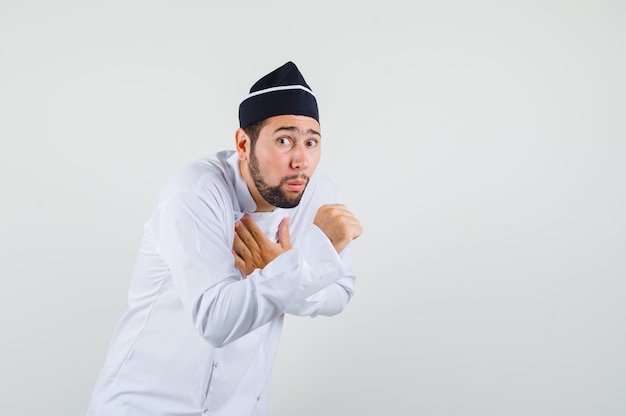 Chef masculino tossindo em uniforme branco e parecendo doente. vista frontal.