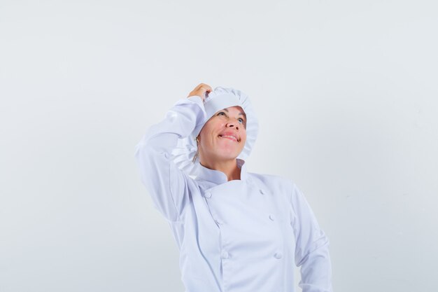 Chef mulher coçando a cabeça em uniforme branco e parecendo pensativa