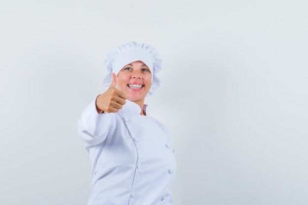 chef mulher de uniforme branco aparecendo o polegar e parecendo feliz