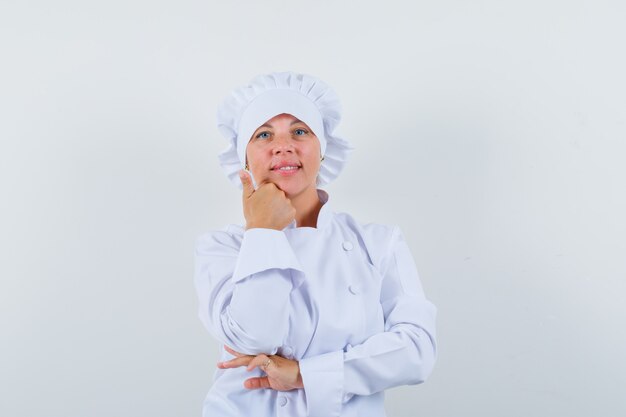 chef mulher segurando a mão no queixo em uniforme branco e parecendo sensato.