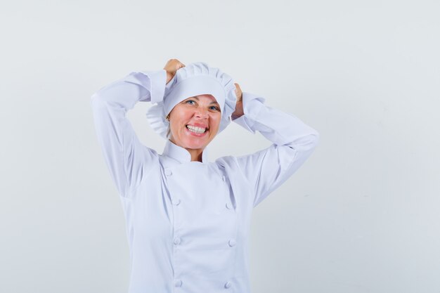 chef mulher segurando as mãos na cabeça em uniforme branco e parece feliz.