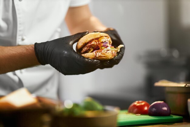 Chef segurando um suculento hambúrguer de carne.