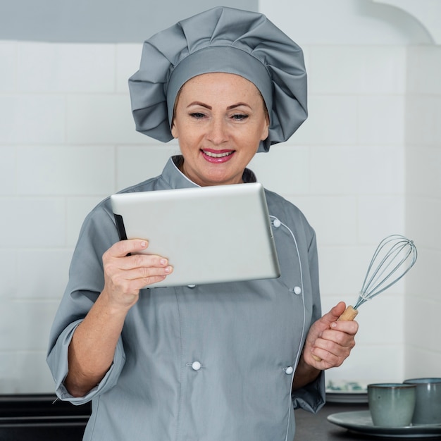 Chef sorridente, olhando para tablet