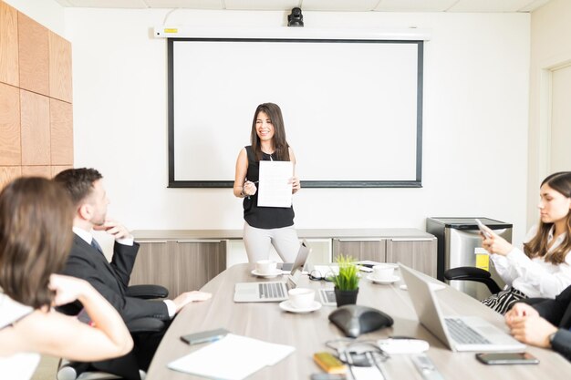 Chefe feminina bem sucedida mostrando análise de mercado para coordenadores na sala de reuniões