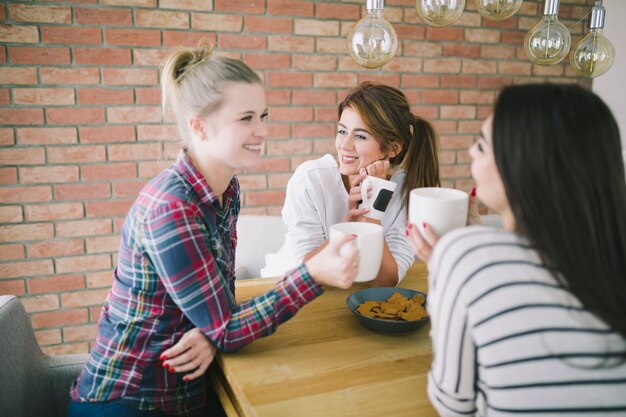 Chicas encantadoras que gostam de chá na cozinha