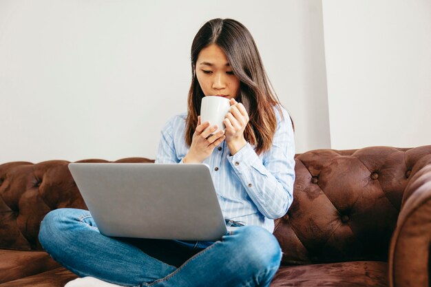 Chilling girl tomando café e assistindo laptop