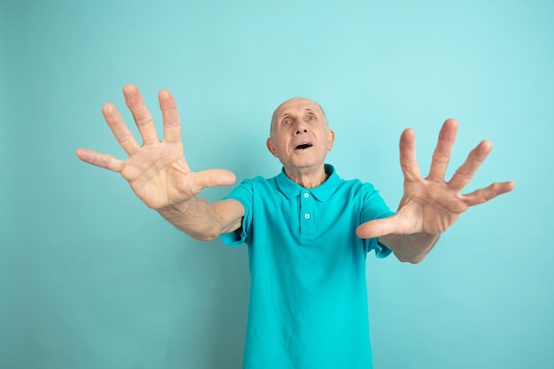 Chocado, com medo. Retrato de homem sênior caucasiano no estúdio azul.