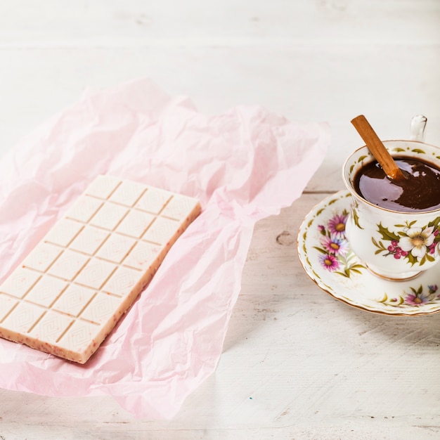 Chocolate branco embrulhado em papel com chocolate quente no copo