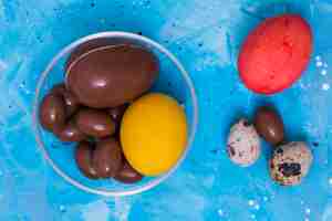 Foto grátis chocolate e ovos de páscoa coloridos na mesa