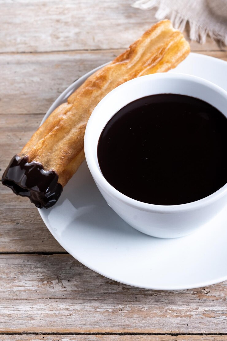 Foto grátis chocolate quente com churros em mesa de madeira