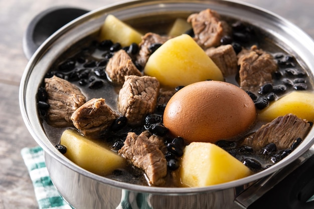 Cholent judaico tradicional em caçarola na mesa de madeira