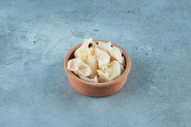 Chucrute fermentado com cenouras em uma tigela na superfície azul