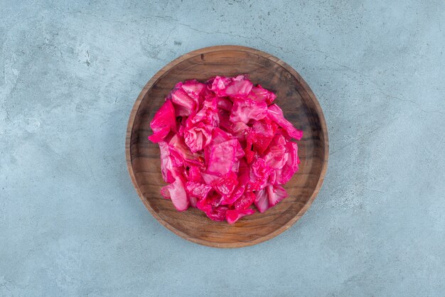 Chucrute vermelho fermentado em uma placa de madeira, na mesa azul.