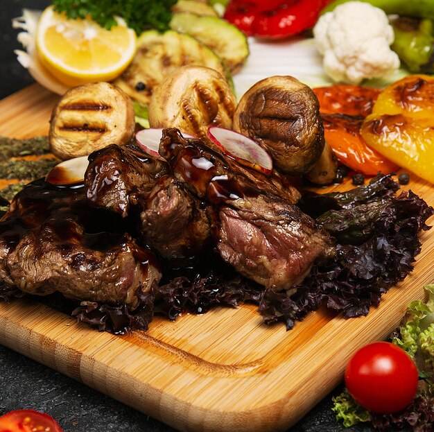 Churrasco, carne grelhada com batatas e batatas fritas vegetais na placa de madeira,